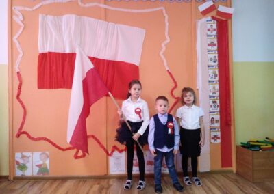 Dzieci z flagą stoją przed tablicą