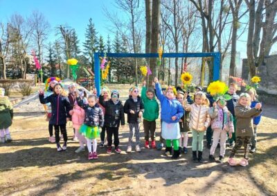 Powitanie wiosny-dzieci trzymają w górze wykonane własnoręcznie kwiaty.